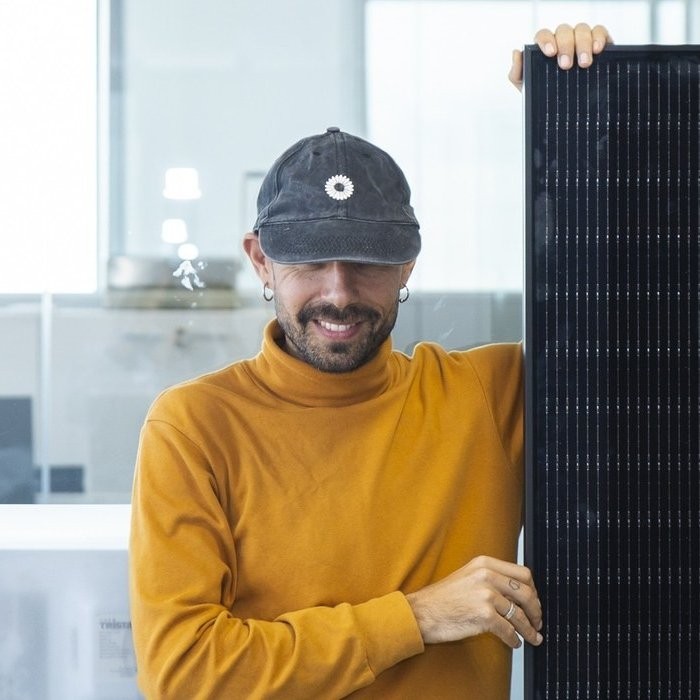 Persona amb la gorra de Recomana i suma al costat d'una placa solar